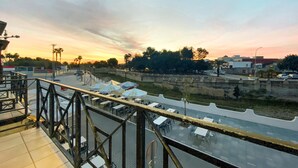 A terrace with outdoor seating and a view of a river and cityscape during sunset. - Artesol in Platja de l Arenal (Els Poblets)