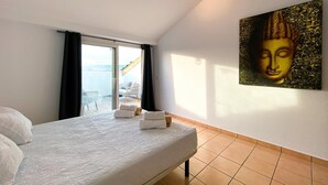 A bedroom with a bed, a large window, a view of the sea, and a Buddha painting on the wall. - Artesol 4 pax in Platja de l Arenal (Els Poblets)