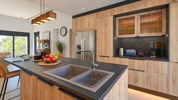 A modern kitchen with a large island, stainless steel appliances, wooden cabinetry, and a built-in wine rack. - Casa Renata 8 pax in Javea (Javea)