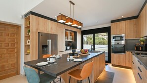 A modern kitchen with wooden cabinetry, a central island, and stainless steel appliances. - Casa Renata 8 pax in Javea (Javea)