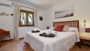 Ein helles Schlafzimmer mit einem großen Bett, einem Holzkopfstück und einem Fenster mit Vorhängen.