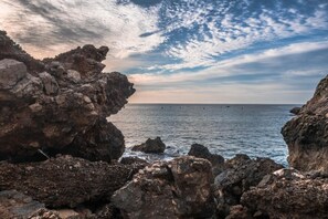 Um litoral rochoso com céu limpo e mar calmo.