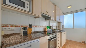 Een keuken met een magnetron, fornuis en oven, een granieten aanrechtblad en een raam voor natuurlijk licht.