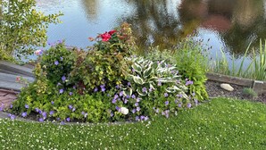 Ein friedlicher Garten mit Teich, üppigem Grün und blühenden Pflanzen.