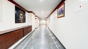 A long, narrow hallway with marble flooring and wooden paneling on the left. - Sapthagiri Hotel Near Saptagiri Circle (Anantapur)