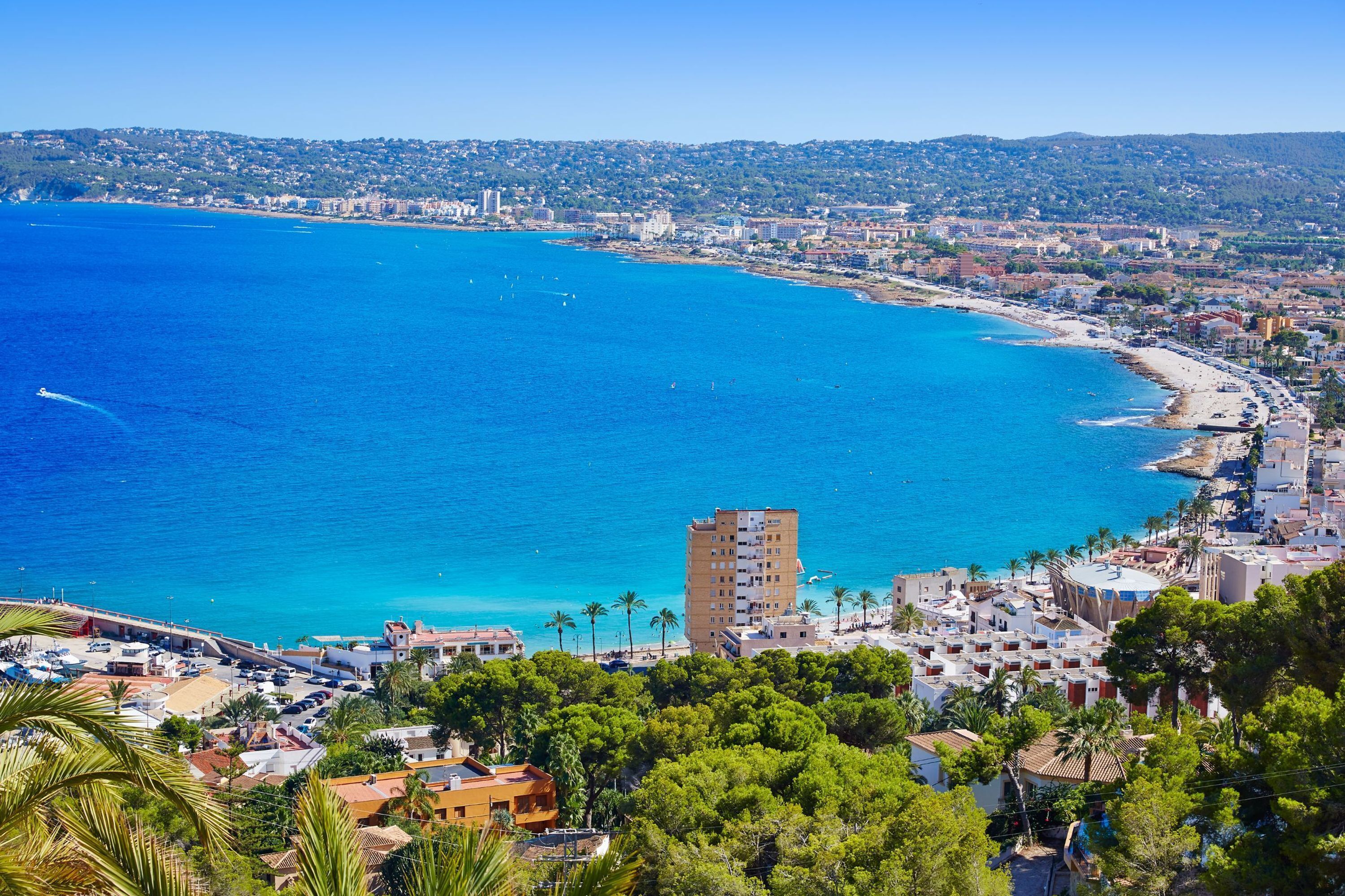 Un paysage urbain côtier caractérisé par une plage bien visible, un immeuble de grande hauteur et des quartiers résidentiels densément peuplés.