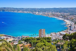 A coastal cityscape with a prominent beach, a high-rise building, and dense residential areas.
