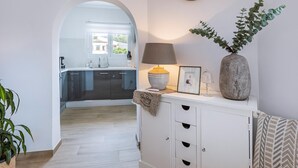 Een moderne keuken met een groot raam, een klok aan de muur en een plant op het aanrecht.