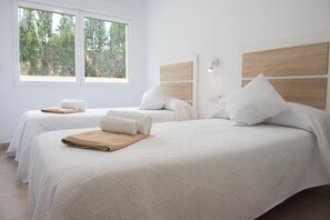 A hotel room with two beds, each with a white bedspread and a rolled towel. There is a window providing a view of trees outside. - Marina B3 4 pax in J vea (Denia)