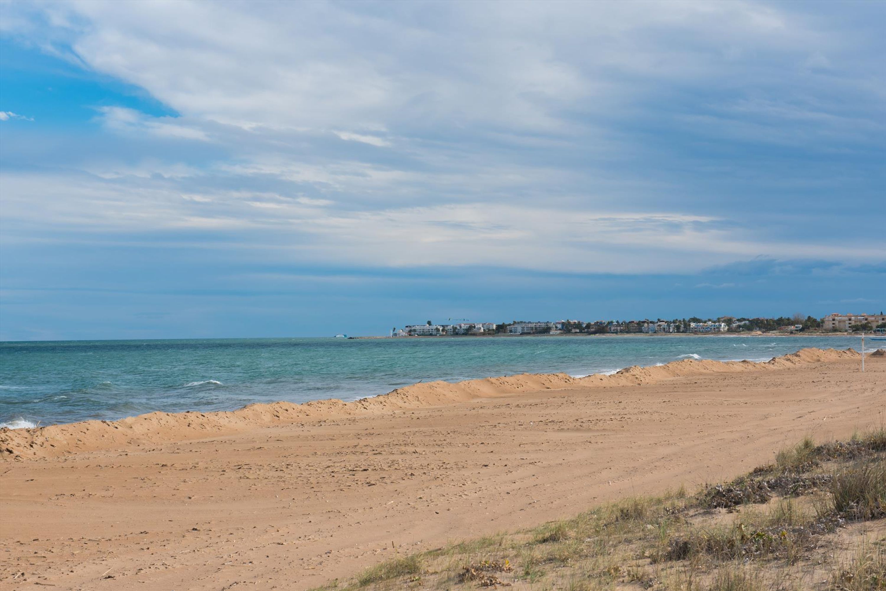 Ein Strand mit blauem Himmel und ruhigem Meer.
