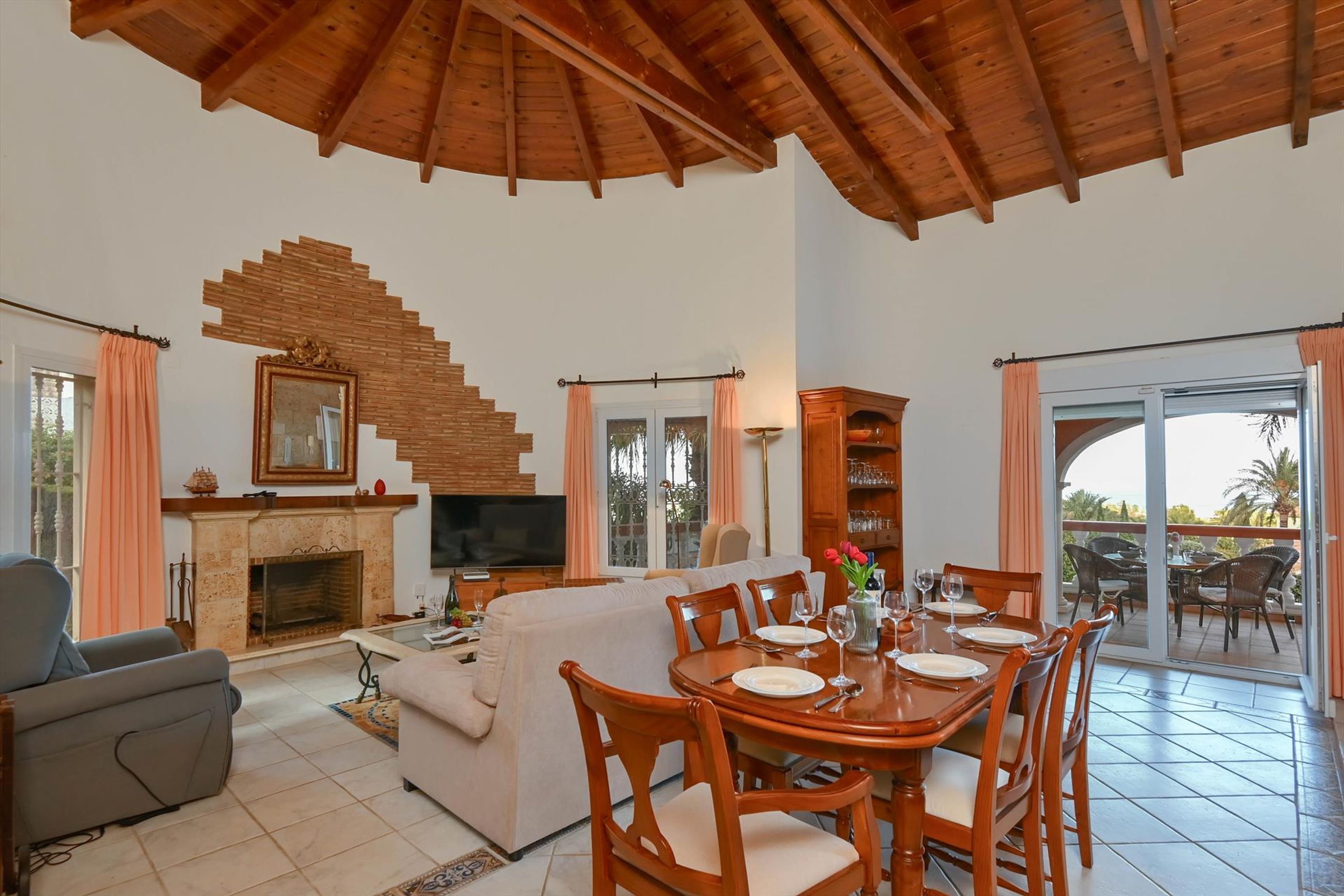 Amplia sala de estar con chimenea, televisor y una mesa de comedor preparada para cuatro personas.