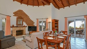 A spacious living area with a fireplace, a television, and a dining table set for four. - Serena Vista in J vea (Denia)