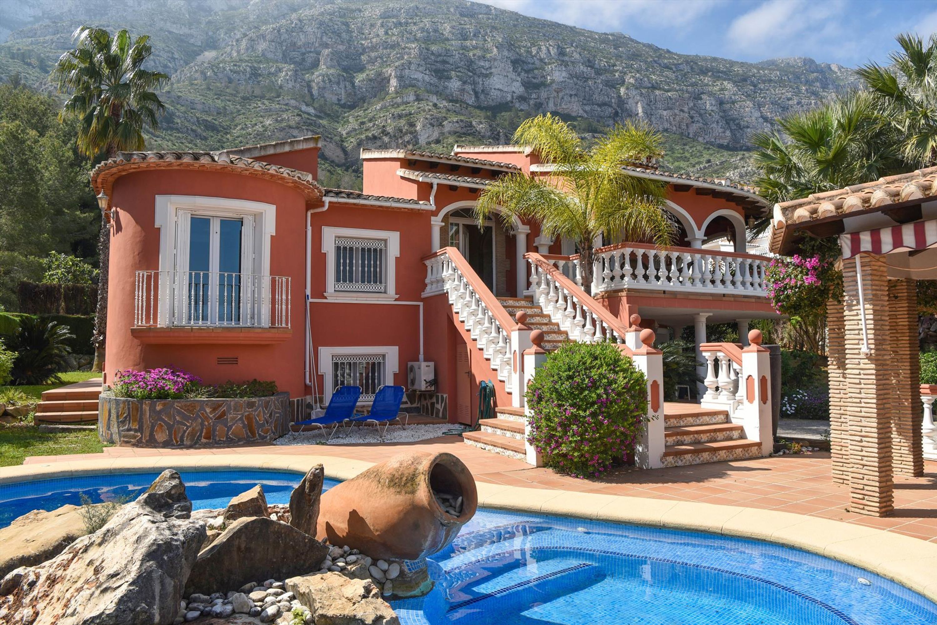 A two-story house with a swimming pool, a staircase, and a view of mountains.