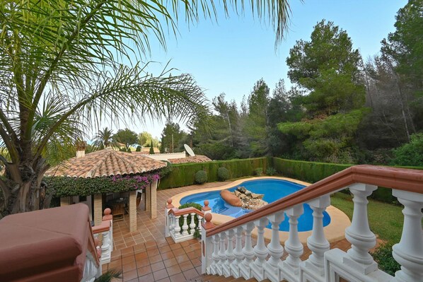 A pool area with a tiled deck, a white balustrade, and surrounding greenery. - Serena Vista in J vea (Denia)