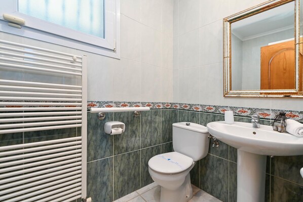 A bathroom with a toilet, sink, and radiator.