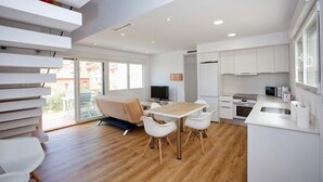 A modern apartment with a dining area, kitchen, and a balcony with a sofa. - Marina B5 in El Tosalet (Denia)