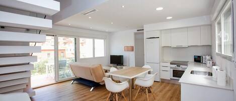 Un appartement moderne comprenant un coin repas, une cuisine et un balcon avec un canapé.