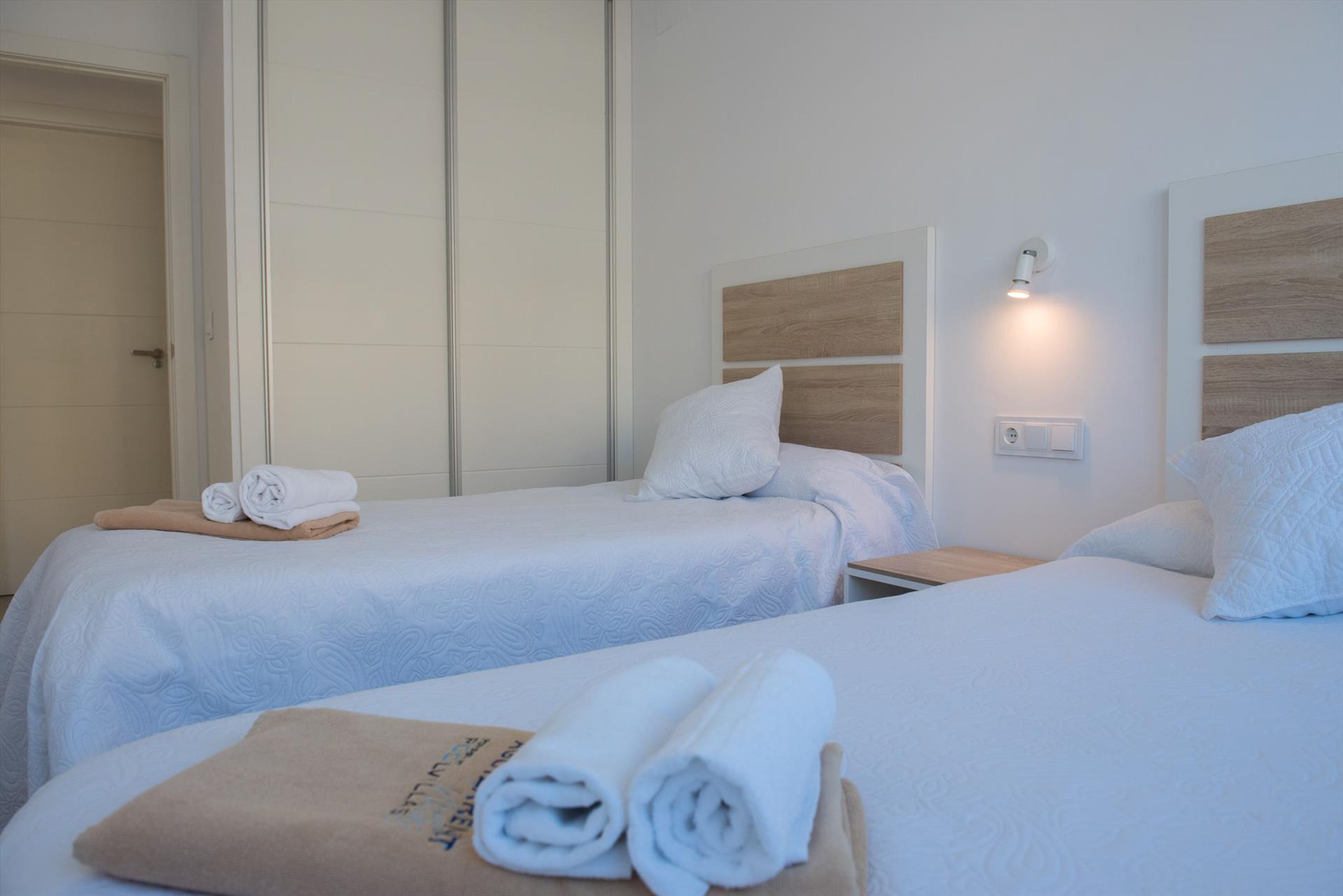 Hotellihuone, jossa on kaksi sänkyä. Kummassakin sängyssä on valkoinen peitto ja tyynyjä, ja etualalla olevalla sängyllä on ruskea pyyhe.