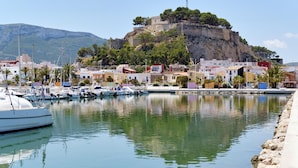 A marina with boats docked, a coastal town with buildings, and a castle on a hill. - Marina B2 4 pax in J vea (Denia)