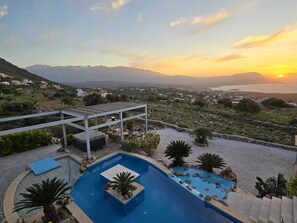 A pool area with a view of the sunset and mountains. - Villa with Ocean View and Heated Pool (Kokkino Chorio)