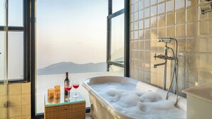 A bathroom with a large bathtub, a glass partition, and a view of mountains. - The English Country House (Mussoorie)