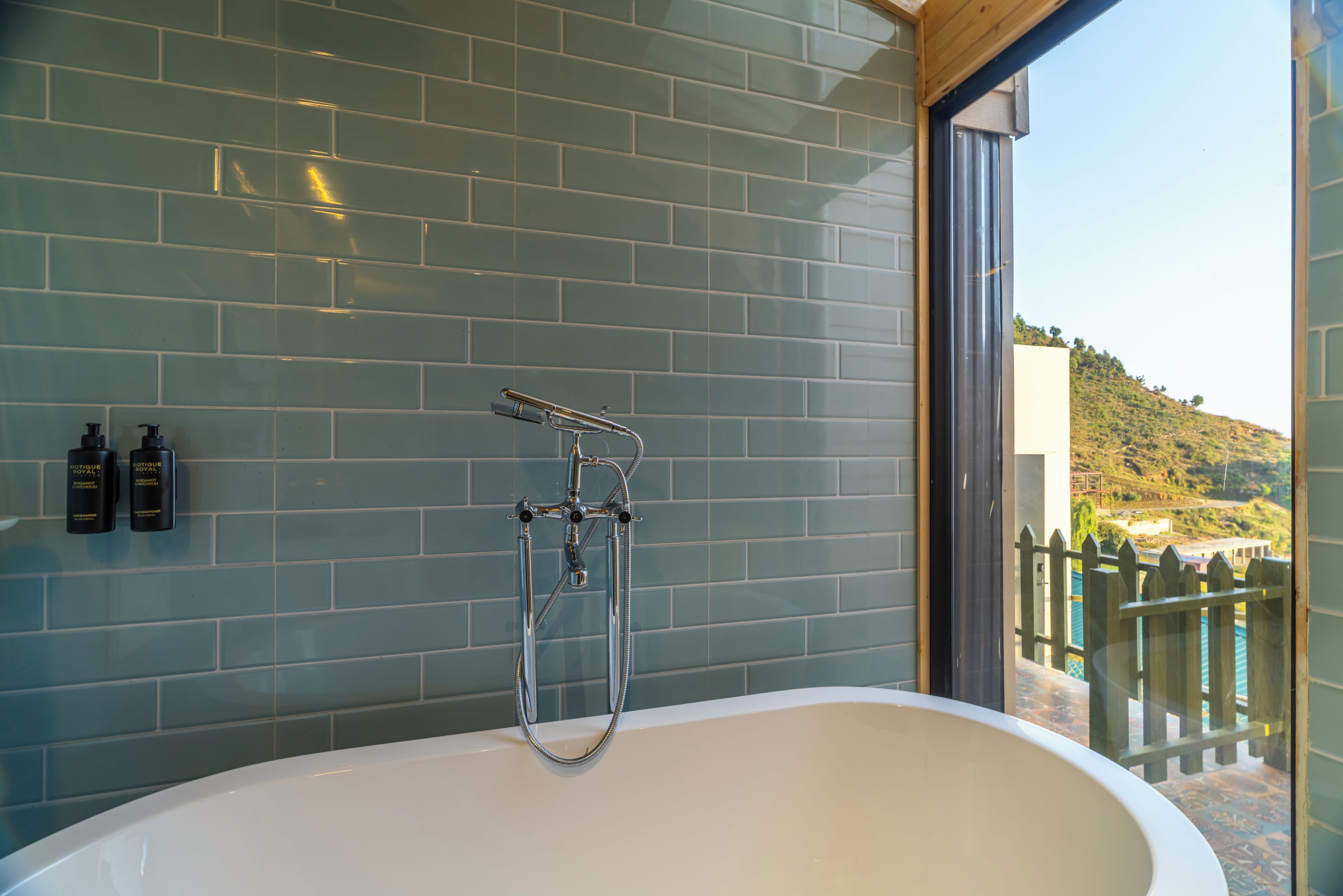 Une salle de bain avec une baignoire sur pieds, une douche à parois de verre et une vue sur une colline.