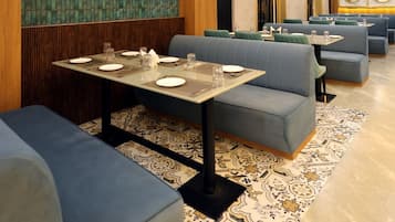 A restaurant interior with booths, tables, and hanging light fixtures.