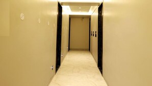 A modern hotel hallway with a marble floor, recessed lighting, and a door at the end. - Hotel RGS Crystal (Kanpur)