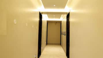 A hotel hallway with a marble floor, recessed lighting, and a door at the end.