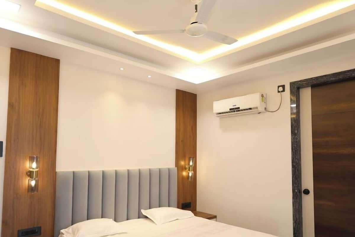 Ein modernes Schlafzimmer mit einem großen Bett, einem Deckenventilator, Einbauleuchten und einer Wand mit Holzpaneelen.