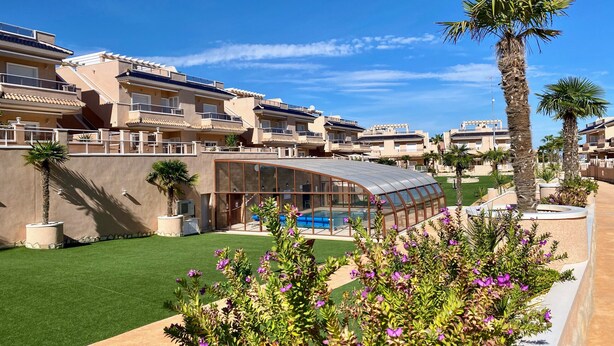 Un hôtel moderne doté d’une piscine, de palmiers et d’une pelouse bien entretenue.