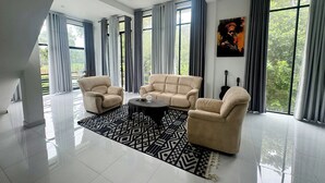A spacious living room with a large window, a patterned rug, and a painting on the wall.