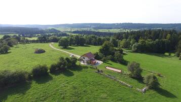 Landgoed in het buitengebied met een boerderij, groene velden en een stenen muur.