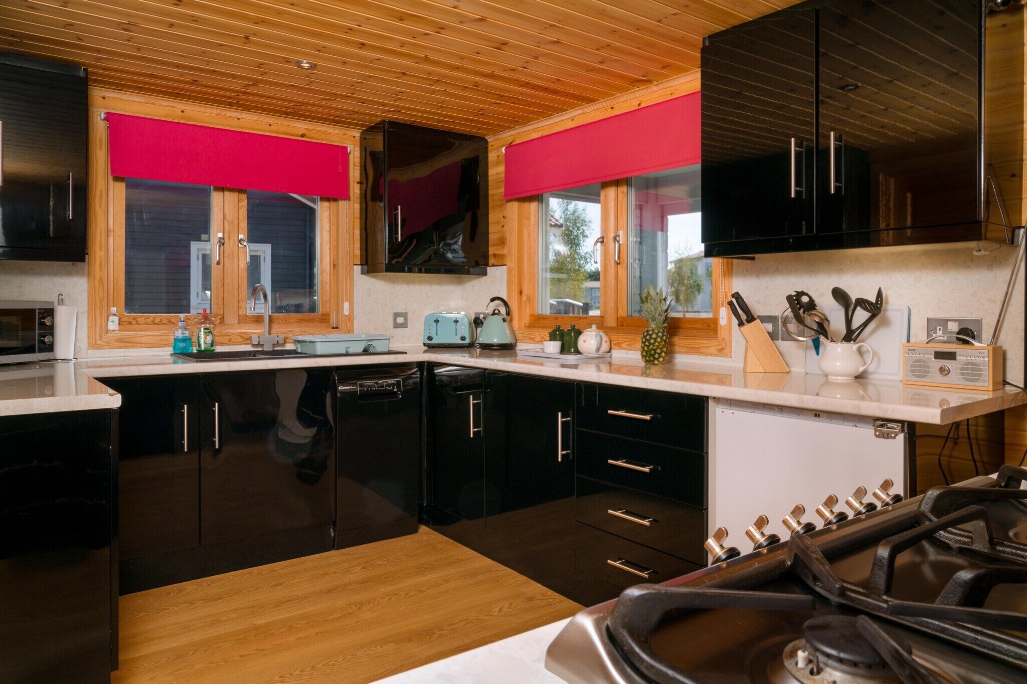 Una cocina moderna con armarios negros, encimeras de madera y una estufa a gas.