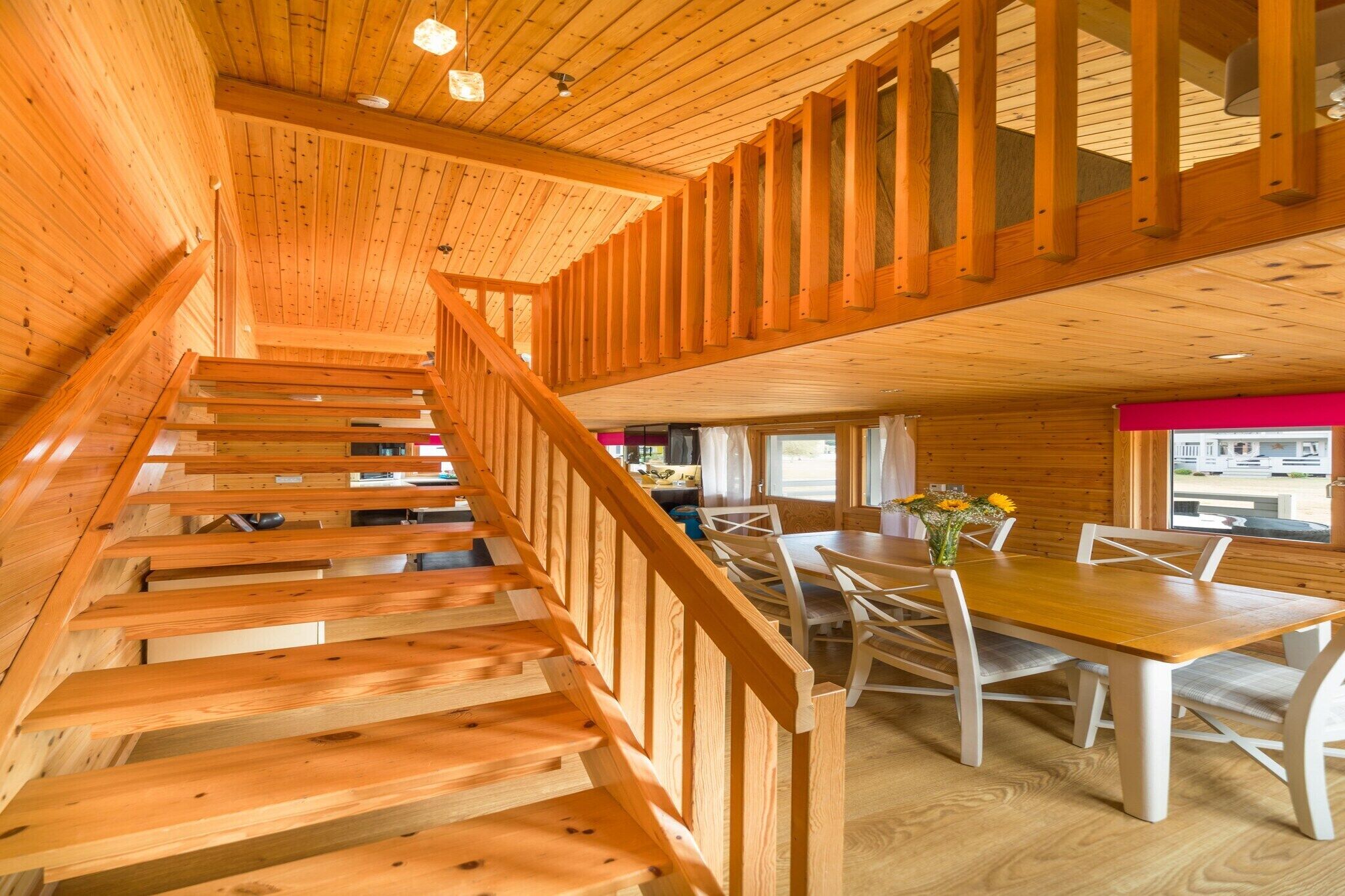 Un escalier en bois mène à un espace repas comprenant une table et des chaises.