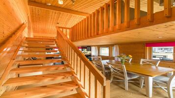 Un escalier en bois mène à un espace repas comprenant une table et des chaises.