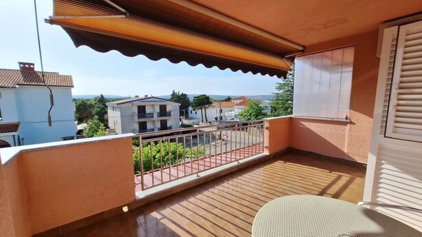 A balcony with a wooden floor, a metal railing, and a view of buildings in the distance. - Apartman Štefica with AC and balcony for 2 people (Punat)