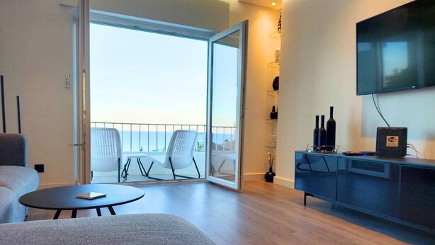 A modern living room with a sofa, a round table, and a balcony with chairs. - PRAIA DA ROCHA - BELO HORIZONTE (Portimão)