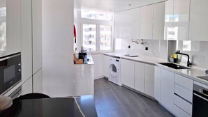 A modern kitchen with white cabinets, a built-in oven, a washing machine, and a sink. - PRAIA DA ROCHA - BELO HORIZONTE (Portimão)