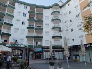 Un immeuble à plusieurs étages doté de balcons, d’un café et d’une terrasse.