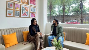 A room with a sofa, a coffee table with a plant, and a window with a view of trees and a red car outside. - Olive Service Apartments - HICC Hitex Hyderabad (Hyderabad)