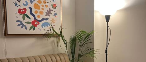 A beige sofa with a laptop, a colorful pillow, and a plant.
