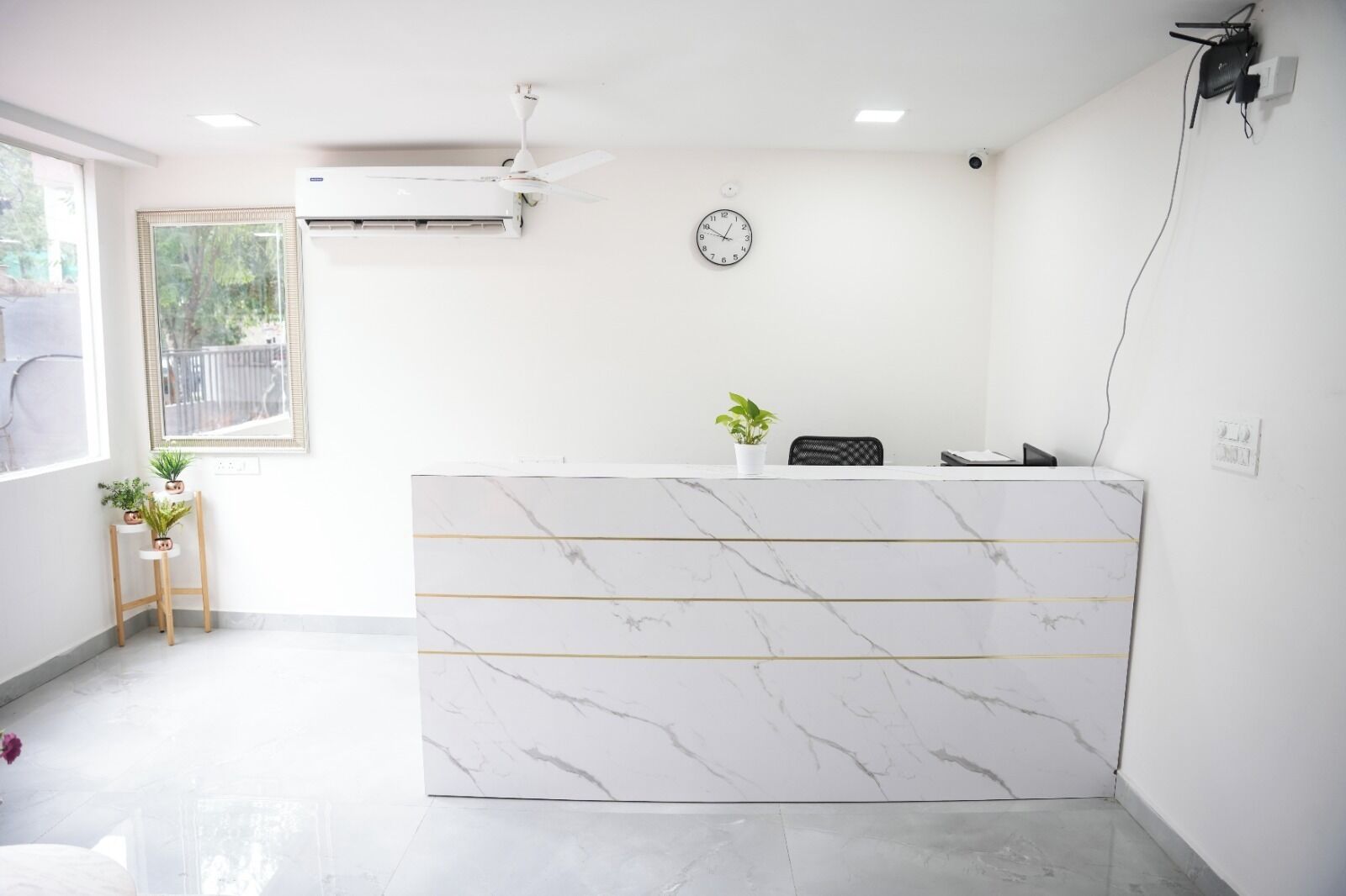 A reception desk with a marble top, a clock on the wall, and a ceiling fan.