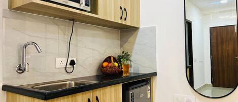 Una cocina con microondas, lavamanos y refrigerador.