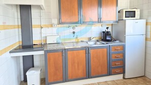 Uma cozinha compacta com armários de madeira, micro-ondas, geladeira e pia.
