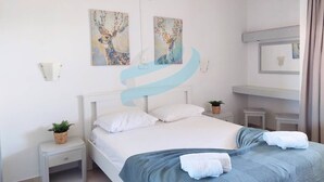A hotel room with a bed, a nightstand, a wall-mounted mirror, and two paintings on the wall. - PRAIA DA ROCHA – CLUB PRAIA DA ROCHA VI (Portimão)