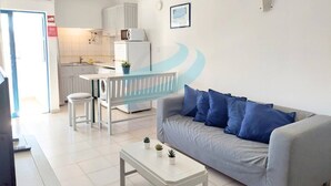 A modern living room with a grey sofa, a white coffee table, and a dining area with a white table and chairs. - PRAIA DA ROCHA – CLUB PRAIA DA ROCHA VI (Portimão)