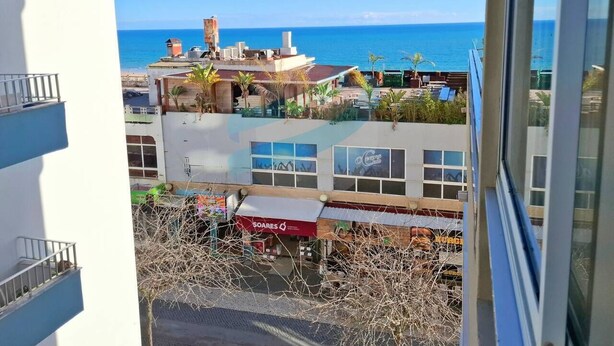 Udsigt fra en balkon over et strandlandskab, med en bygning i forgrunden.