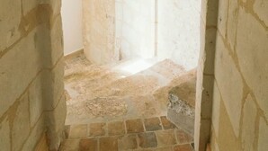 A narrow stone corridor with an arched doorway leading to a room with a tiled floor. - La Belle Tuffière (Montreuil-Bellay)
