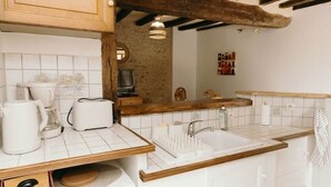 A kitchen with white tiles, wooden countertops, a sink, and a hanging light fixture. - La Belle Tuffière (Montreuil-Bellay)